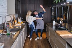 Excited couple dancing in aprons together in kitchen