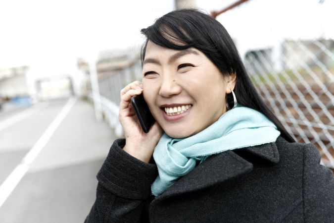 Smiling East Asian woman having a phone call outdoor