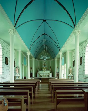 Inside view of a chapel with pews, pillars, an altar, chandelier and statues