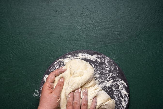 Hands kneading dough with flour