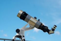 Single solar telescope against clear blue sky.