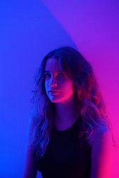 Portrait of teenage girl in purple in dark top lit studio