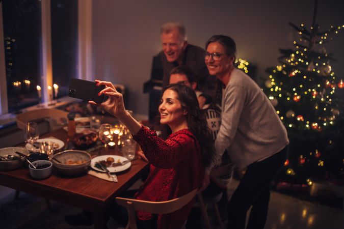 Adult family taking selfie with mobile phone at the dinner table on Christmas