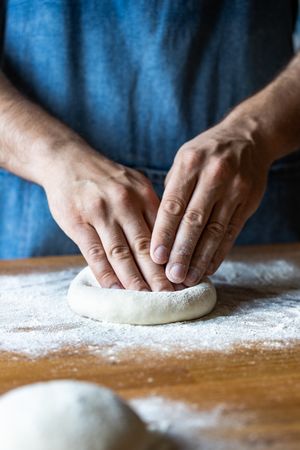 Crop man flattening dough for pizza