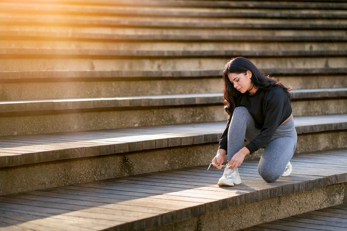 young brunette woman tying her shoes getting ready to exercise
