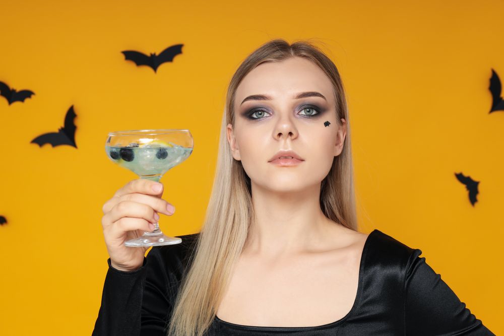 Concept of Halloween, young woman on yellow background