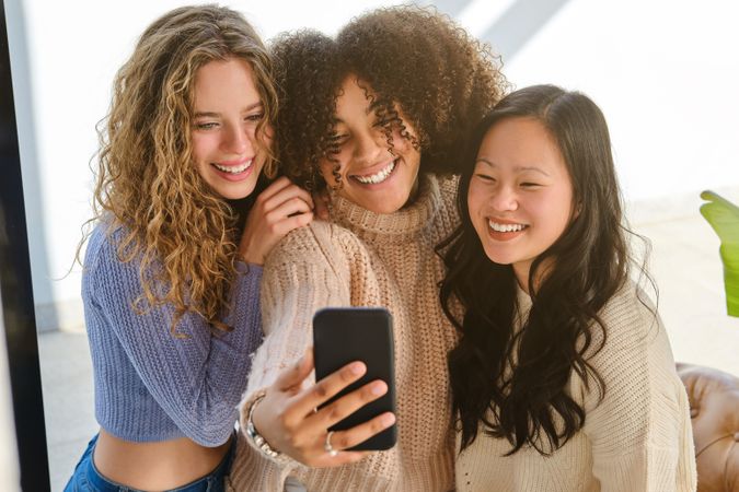 Cheerful diverse girlfriends taking selfie