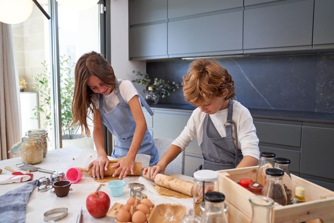 Focused children preparing dough for cookies in kitchen