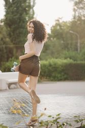 Back of smiling female teenager with skateboard in park with trees in background