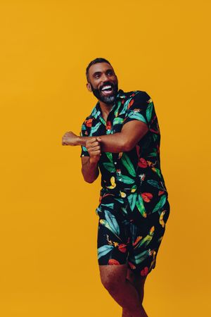 Smiling male dancing in brightly patterned shirt and shorts