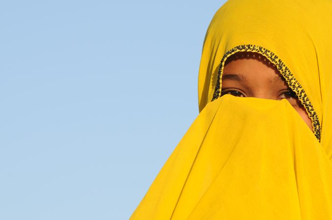 Close-up of girl in yellow Hijab covering her face