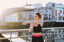 Woman stretching on embankment near water