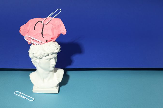Bust of David with crumpled post it note with question mark and paper clips, copy space