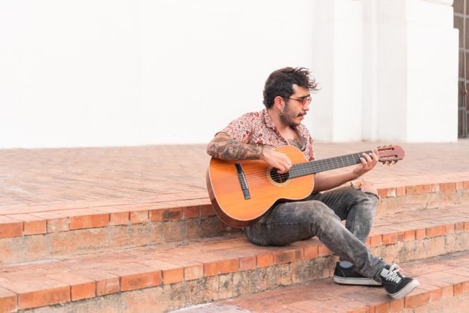 Street musician playing guitar on a staircase in the street