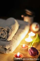 Towels on brown wooden table near lit candles bedYG4