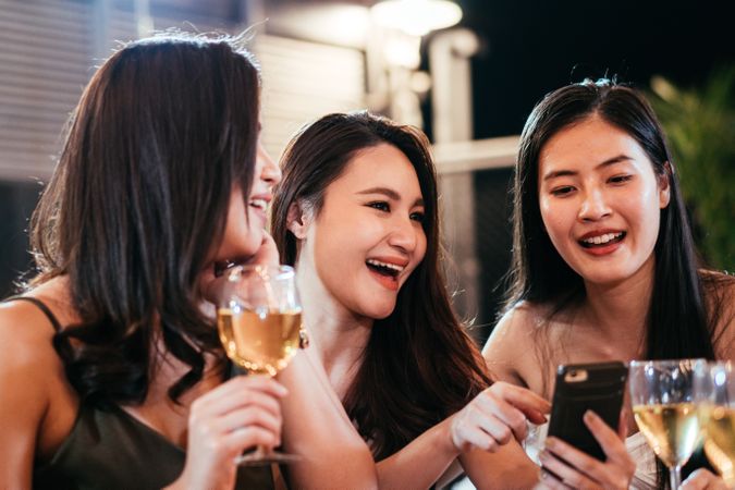 Group of woman watching video on mobile phone in bar
