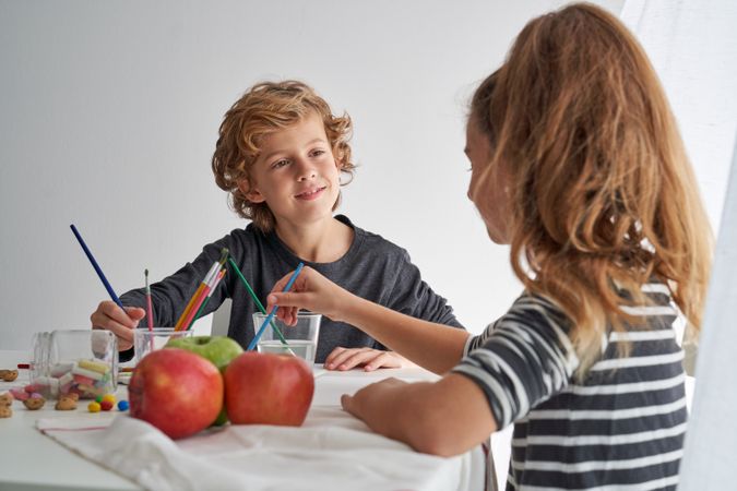 Boy painting near girl at table
