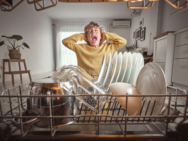 Boy screaming near dishwasher with kitchenware