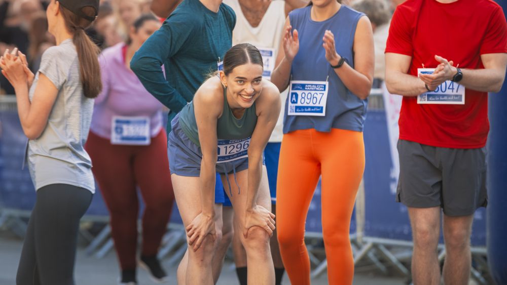 Portrait of Athletic Female Jogger Resting and Celebrating After Crossing the Finish Line in a Marathon