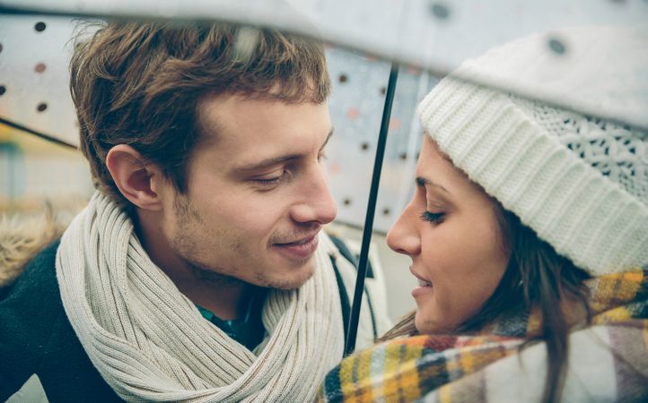 Affectionate couple under umbrella together on cold day