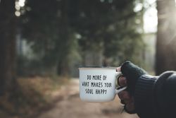 Crop hand with motivational mug in forest