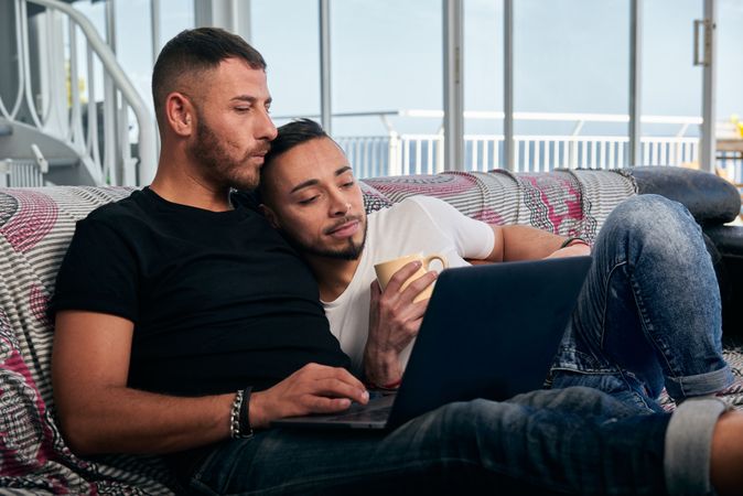 Happy gay couple using laptop at home