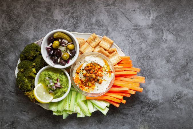 Tasty hummus and sauces decorated with bright cut vegetables on table