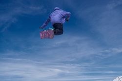 Unrecognizable snowboarder jumping on slope