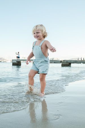 Happy toddler playing with water on beach