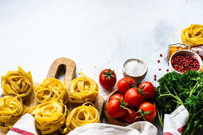 Uncooked Fettuccine pasta and fresh vegetables on counter with copy space