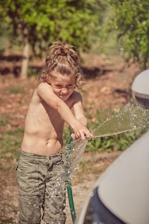 Cheerful boy with hosepipe on grass