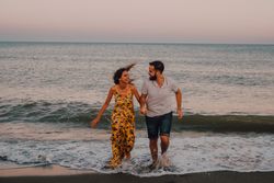 Lovely couple running holding hands on sandy beach