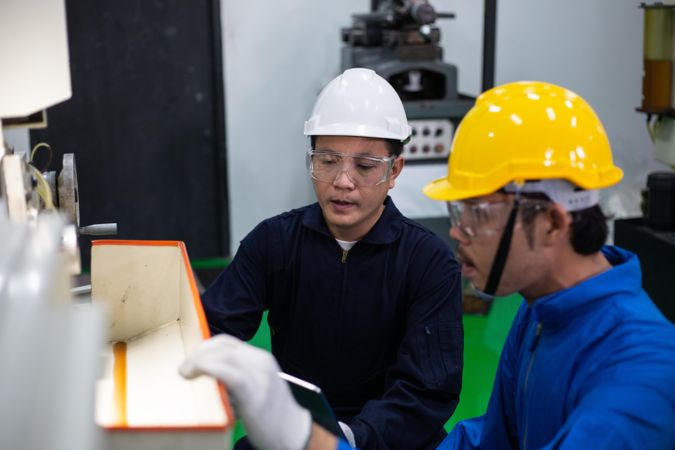 Two Asian males working together in industrial plant