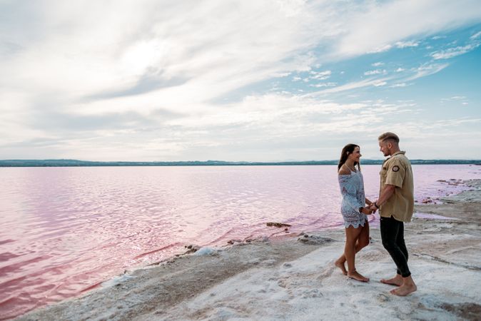 adorable couple standing on an amazing beach with pink water