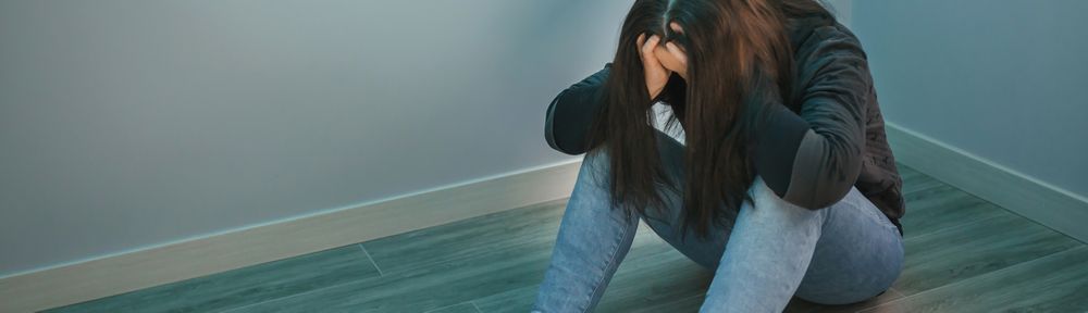 Woman with problems with hands in head sitting on the floor