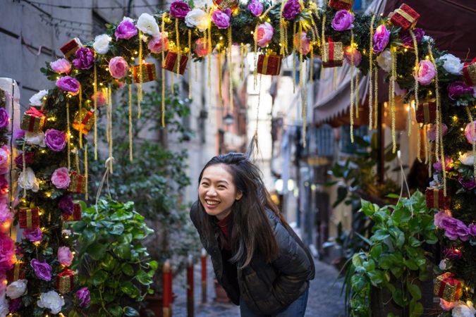 Satisfied Asian female traveler in casual wear walking on festive beautiful street