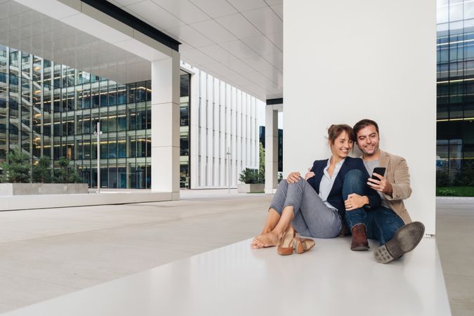 Businesspeople hugging and using smartphone on street