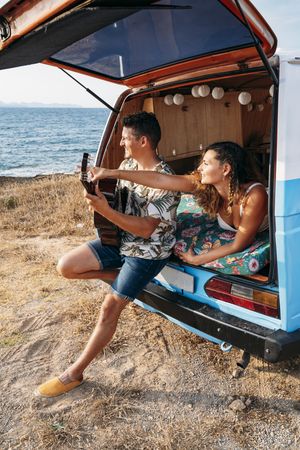 Amorous man plying on guitar and looking at woman in trunk of car