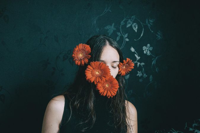 Studio portrait of woman with gerbera flowers on her face