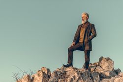 Man in brown coat standing on brown rock during golden hours