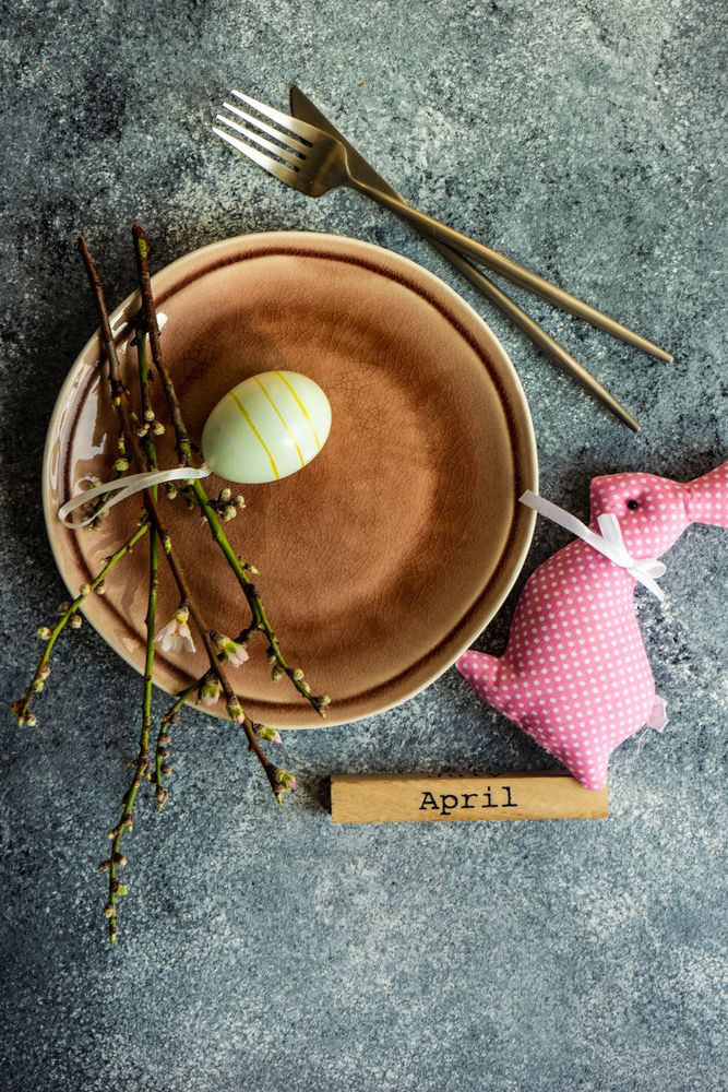 Easter table setting on grey counter with decorative small yellow egg and pink rabbit ornament