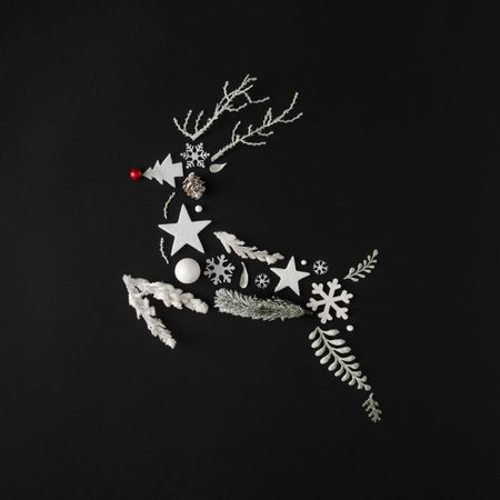 Reindeer on dark background made of leaves and snowflakes