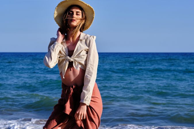 A fashion model with a hat at the beach before sunset