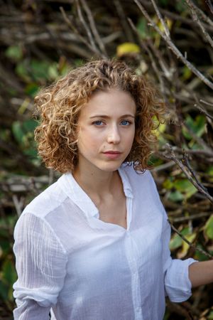 Young woman near dry twigs of bushes