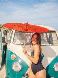 Woman with red umbrella at car on beach