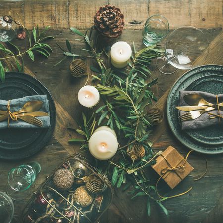 Festival holiday table setting on wooden table, with gold ornaments, branches, square crop