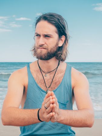 Man training yoga on beach