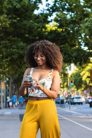Stylish Black woman using smartphone on street