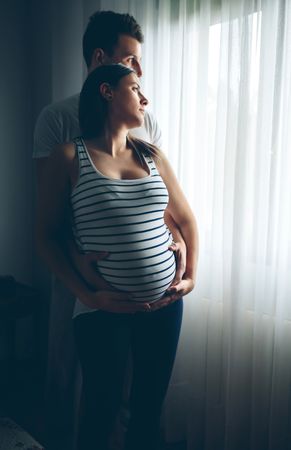 Pregnant woman embraced by her husband