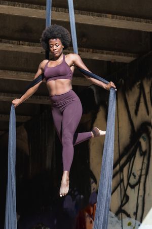 Female doing yoga with aerial silks in city